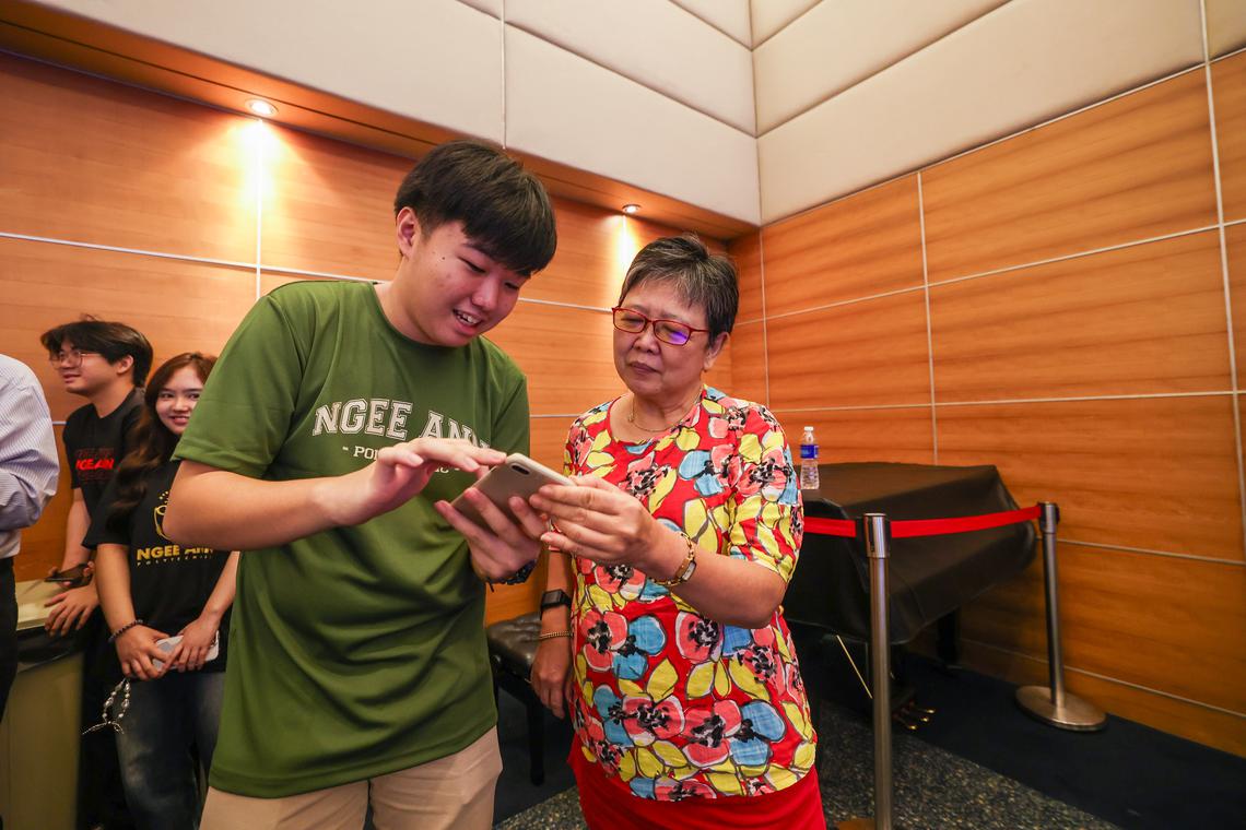 义安理工华文传媒系学生丘瑞安(左)星期三参加数码学堂,从旁为年长者提供技术指导,包括教导参与者黄美兰(右)如何使用手机应用等。(白艳琳摄)