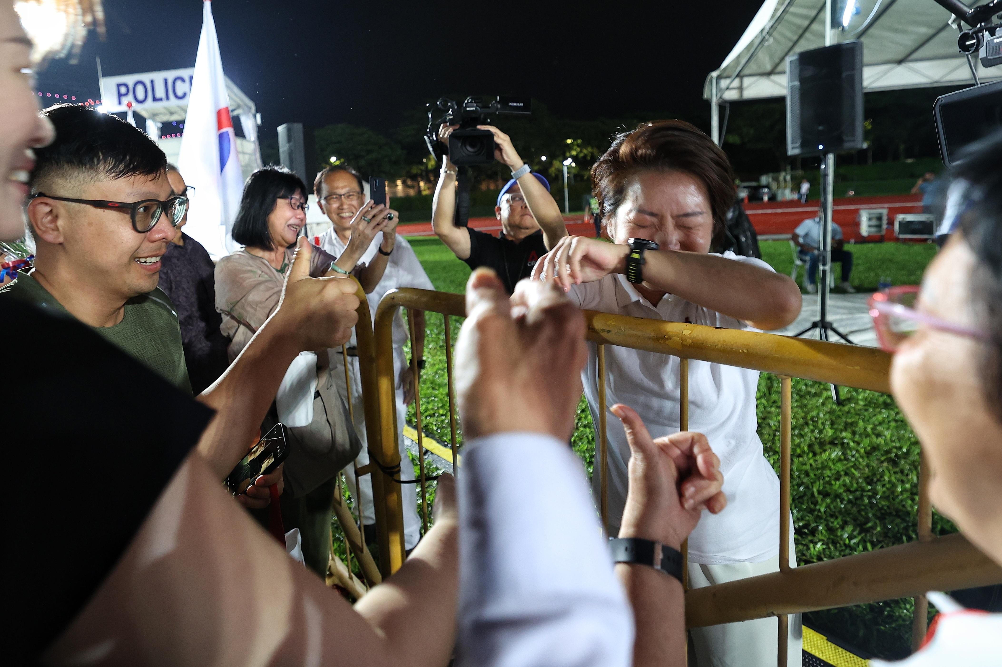 人民行动党蒙巴登区候选人吴诗琪(右一)在群众大会现场发言后,看到居民对她的热烈支持,激动落泪。(郑一鸣摄)