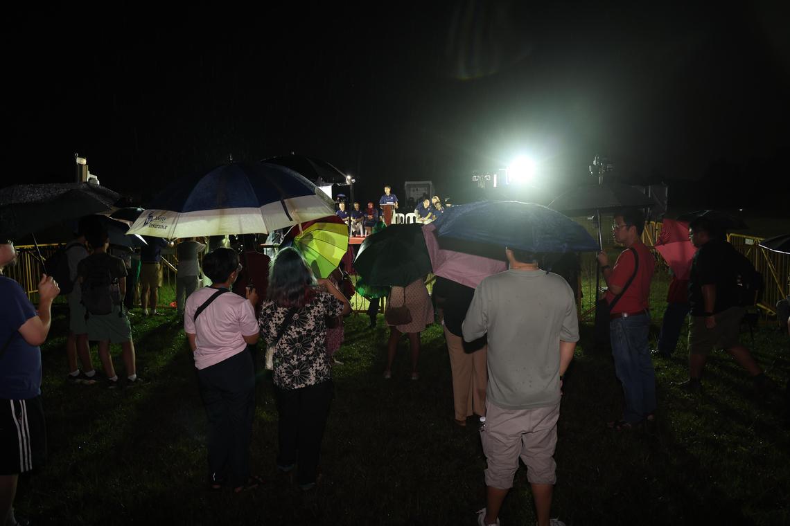 尽管下起细雨,仍有不少公众撑伞到裕华园地铁站旁的文礼大道草场,听红点同心党候选人发表演讲。(邬福梁摄)