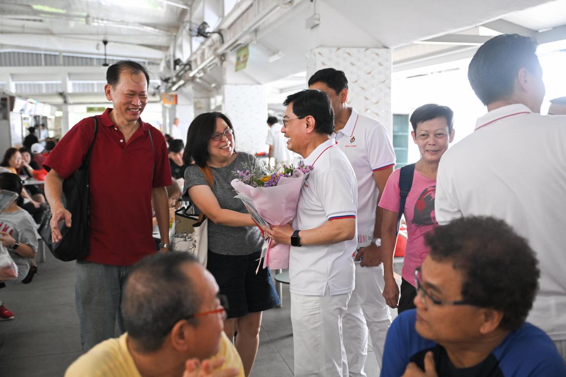 已经宣布引退的王瑞杰副总理(左三站立者),为人民行动党东海岸竞选团队拉票,有居民献花感谢他的照顾与协助。(海峡时报)