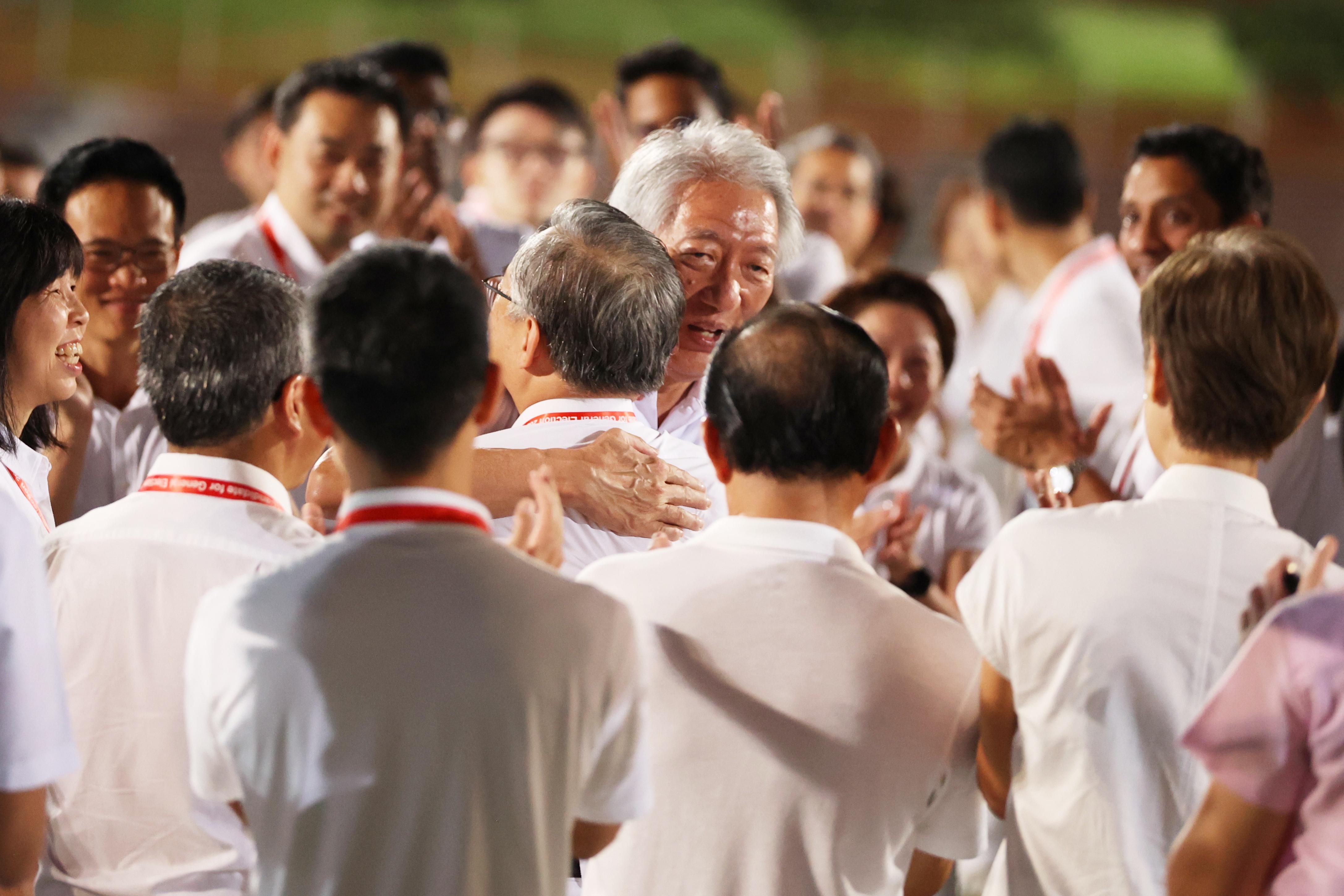 原白沙—榜鹅集选区领军部长张志贤(中间)引退后,由副总理兼贸工部长颜金勇(背对镜头)接手带领榜鹅集选区团队。等候正式结果出炉之前,张志贤在行动党位于勿洛体育场的集合中心与颜金勇拥抱,以示鼓励。(何家俊摄)