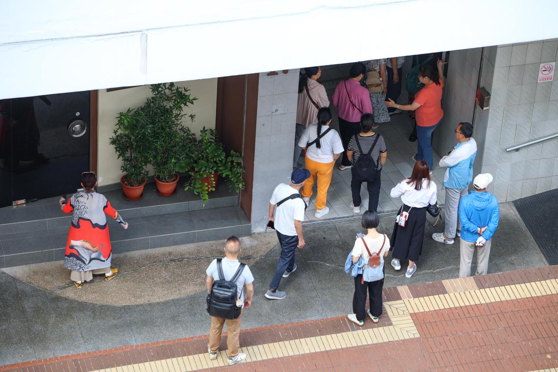 从早上10时起,陆续有载着游客的旅游大巴来到店外,每辆车至少15人。两名女员工负责在一楼电梯口接待,一些穿制服的员工则在楼上带着对讲机。(关俊威摄)