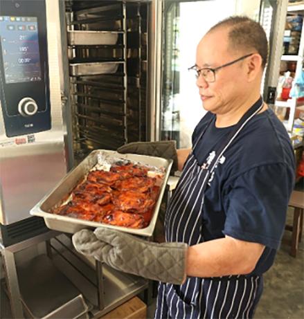 吴金宝在现有厨房学习烹煮红烧鸡肉。新厨房的面积将是现有的六倍,不仅能容纳更多学员接受培训,也有助提升餐饮产能。(突破宣道之家提供)