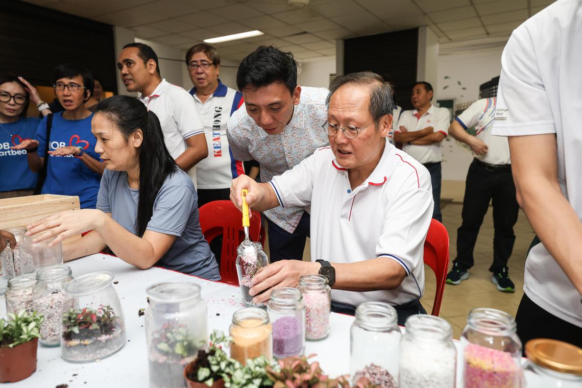 领军蔡厝港集选区的人力部长兼贸工部第二部长陈诗龙医生(右一)星期六出席社区活动,尝试利用玻璃瓶打造盆栽。其他蔡厝港集选区议员萧振祥(右二)和周凯年(右四)也在场。(关俊威摄)