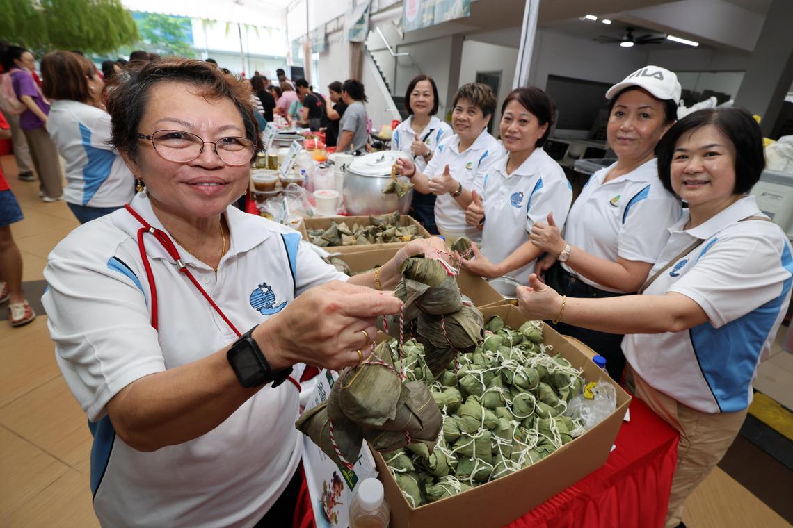 琼州天后宫董事欧宗谚(左一)和同伴们一起在“端午嘉年华”上售卖手包粽子。(梁麒麟摄)