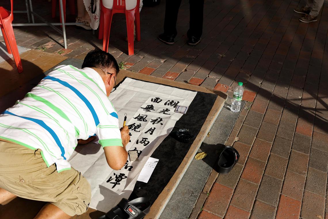 公开组毛笔书法第三名、硬笔书法优秀奖得主陈德利(66岁)现场参赛时,认为桌子限制发挥空间,选择就地挥毫。(陈心媛摄)