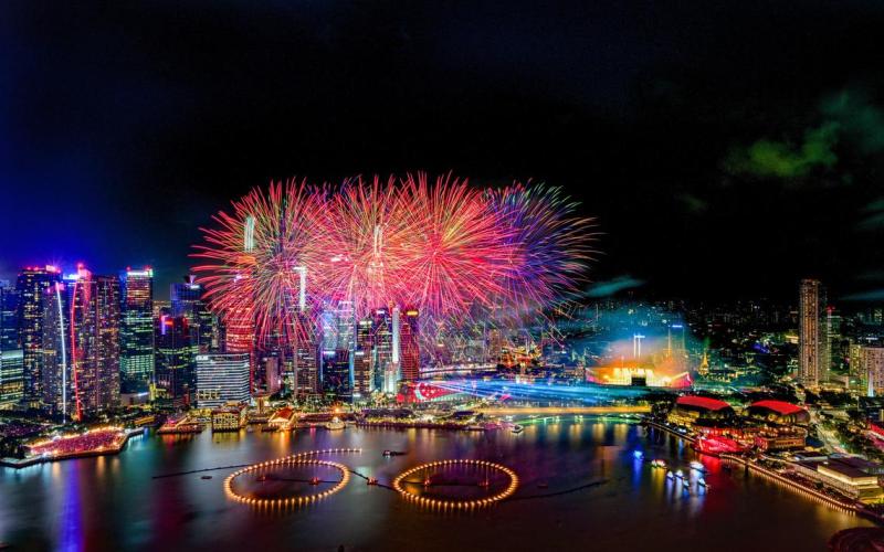 2025年国庆庆典落幕前，璀璨烟花在滨海湾上空绽放，点亮天际线。“60”字样映现水中，为我国建国60周年献上祝贺。（唐家鸿摄）