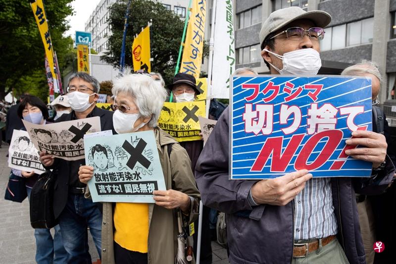 日本示威者4月13日在首相官邸外高举旗帜和海报，抗议日本政府计划将福岛核电站的核污水排放到海洋中。（法新社）