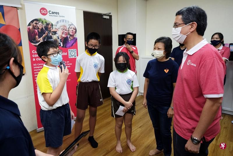 内政部兼国家发展部政务部长费绍尔副教授（右）昨天到位于义顺的CampusImpact中心，见证谅解备忘录签署仪式，并接受孩子们的“访问”，向他们述说自己的成长经历。（曾坤顺摄）