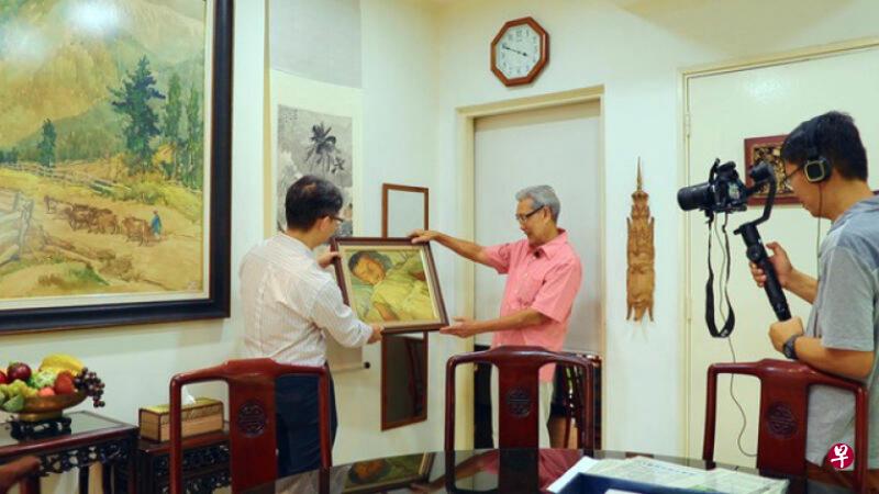 陈志锐（左）采访书画家陈宗瑞大儿子陈威利（中），他们手持的画作是后者4岁睡觉时，父亲为其画的肖像。右为摄影师方壮国。