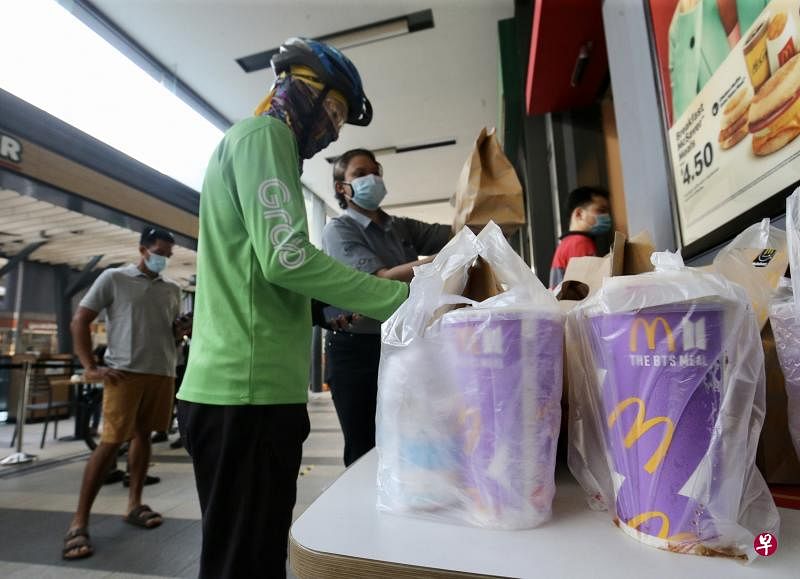 巴耶利峇广场的麦当劳分店在上午11时20分左右，出现大约15名送餐员陆续骑车前去领取BTS套餐。为确保送餐员不跟麦当劳餐馆的职员接触，麦当劳安排送餐员在距离餐馆门口三米外的地方等候，轮到他们时才上前取餐。（邬福梁摄）