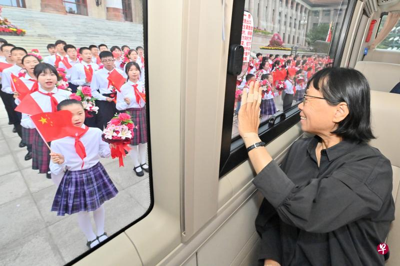 　推动创建中国第一所公办免费女子高中的 “七一勋章”获得者张桂梅抵达北京人民大会堂时向车外的少年儿童致意。（新华社）