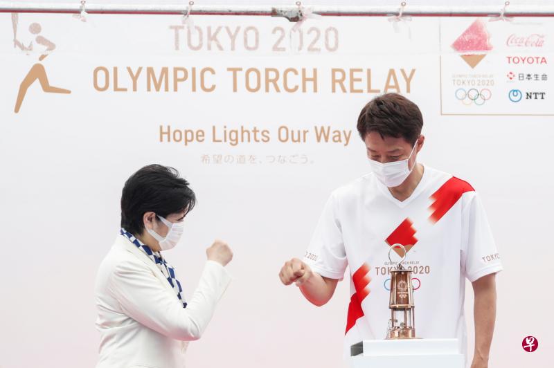 日本网球名宿松岡修造（右）与东京都知事小池百合子（左）击拳致意，准备拿起面前的奥运火种。（路透社）