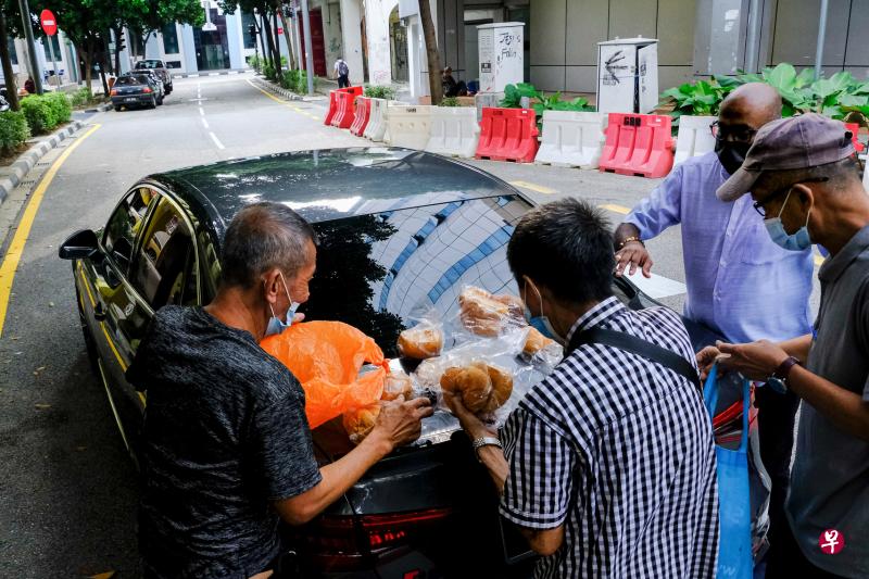 马国抗疫之路还看不见尽头，大部分地区仍全面封锁，许多人生计受影响，三餐难以为继。图为在疫情严重的首都吉隆坡，不少人领取善心人士捐赠的面包果腹。（彭博社）
