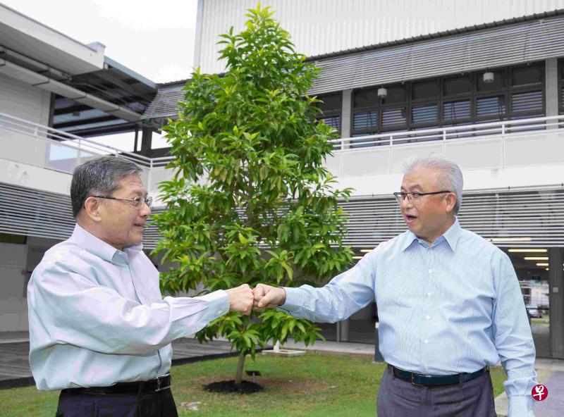 新加坡福建会馆新任会长蔡其生（右）接过陈精毅的棒子，将继续带领福建会馆为社群做出贡献。两人背后是李显龙总理2019年参观福建会馆文化学院时种植的白玉兰树。（陈来福摄）