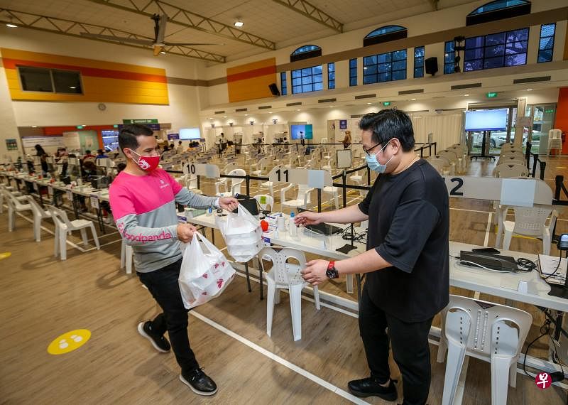 送餐平台FoodPanda和本地四个餐饮品牌合作，准备2000多份餐食给超过40个疫苗接种中心的员工和志愿者。图为FoodPanda营运董事卡利克斯托（左）到拉丁马士民众俱乐部将餐食转交给接种中心值班经理罗善辉（音译）。 （叶振忠摄）