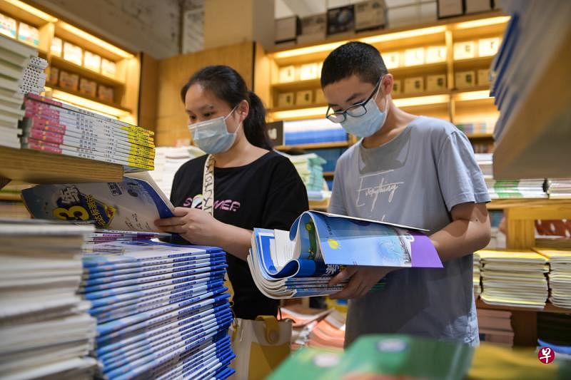 中国竞争激烈的考试选拔制度下，“双减”政策难以消除家长对孩子考试成绩的焦虑。图为一名家长和孩子昨天在安徽省会合肥一家书店内选购教辅资料。（新华社）