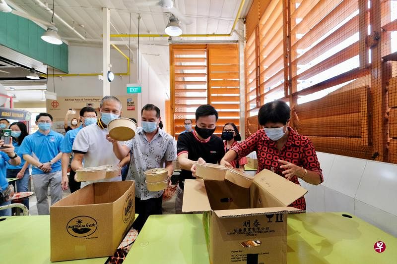 ▲星展银行推出小贩中心认养计划，昨天向丹戎巴葛坊小贩中心的摊贩团购600份餐食分发给受益团体。总理公署部长兼财政部及国家发展部第二部长英兰妮（前排右一）、国家发展部兼通讯及新闻部政务部长陈杰豪（前排左二），以及基层组织义工和银行职员一起准备食物。随行的有星展银行新加坡总监兼董事总经理许志坤（前排右二）和新加坡消费银行部主管苏孝进（前排左一）。（龙国雄摄）