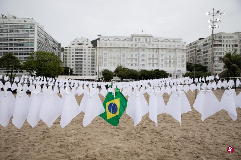 巴西的累计冠病死例已超过60万起，民众在里约热内卢的旅游胜地科帕卡瓦纳沙滩挂起白色手巾和巴西国旗，悼念逝世者。（彭博社）