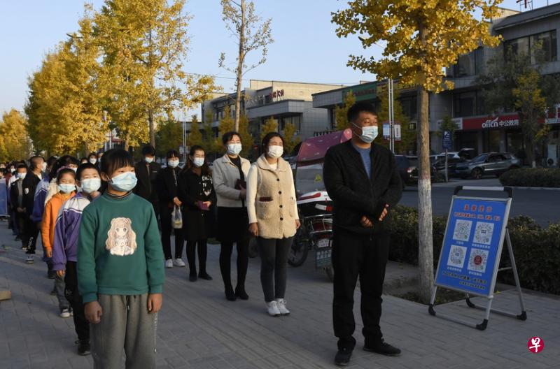 近日暴发疫情的甘肃，多地前天启动3岁至11岁儿童的冠病疫苗接种工作。图为该省永靖县的学生在家长的陪护下排队等候接种疫苗。（新华社）