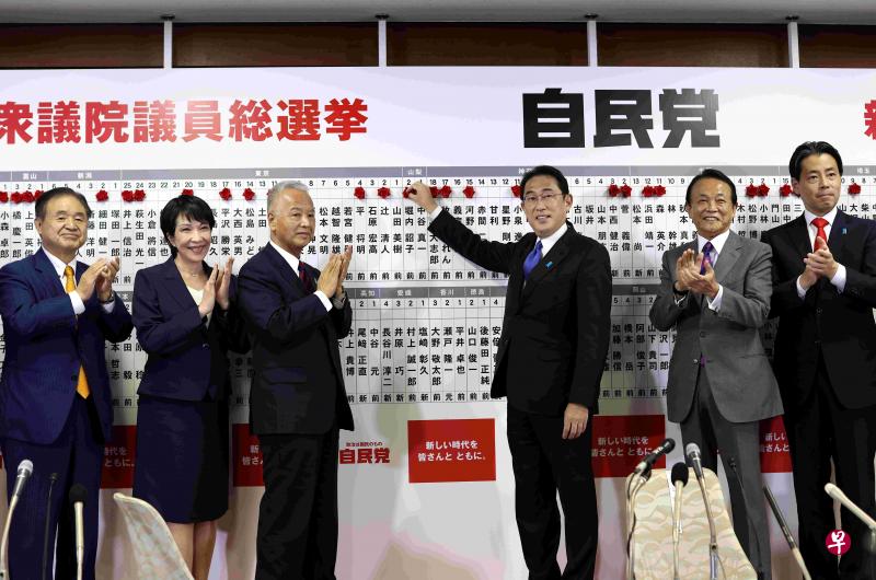 日本首相岸田文雄（右三）在前副首相、自民党副总裁麻生太郎（右二）等人陪同下，昨晚在自民党总部为该党中选候选人看板扣上一朵红花。（路透社）