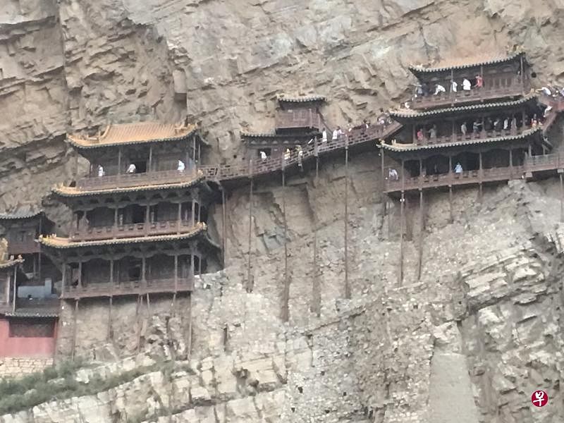 “悬挂”峭壁千年的悬空寺左侧最高第三层即三圣殿（上图，小白点为游客），殿内体现三教合一思想的儒释道三圣并列（下左图）。2018年作者（右二）夫妇与收藏家杨应群夫妇同访山西浑原悬空寺（下右图），为作者二度造访。