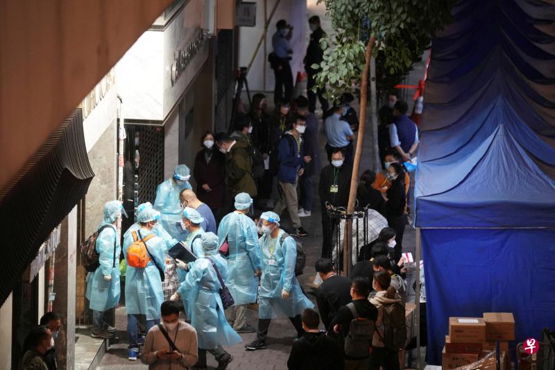 香港湾仔一栋大厦7日晚上被围封，身穿防护服的工作人员为大厦居民进行冠病检测。该大厦有一名住客被列为源头不明的初步确诊个案，初步显示涉及变种病毒株。（路透社）