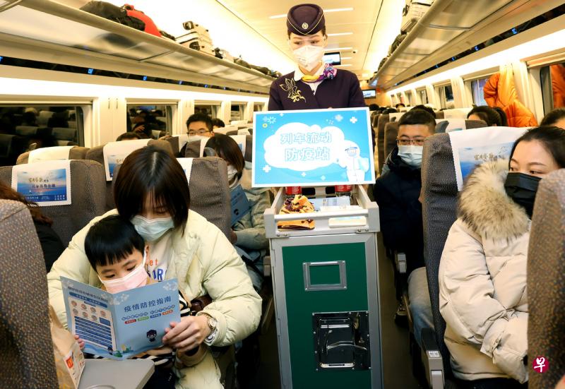 2022年中国春运将从今天开始，2月25日结束，共计40天。图为乘务员在上海虹桥开往汉口的列车上，向旅客分发防疫宣传册。（新华社）