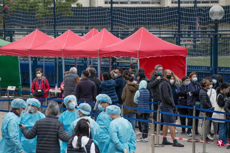 由于愉景湾、沙田及天水围的污水样本对冠病病毒检测呈阳性，港府要求曾身到这些地方的人接受强制检测。图为愉景湾的居民排队等待接受核酸检测。（彭博社）