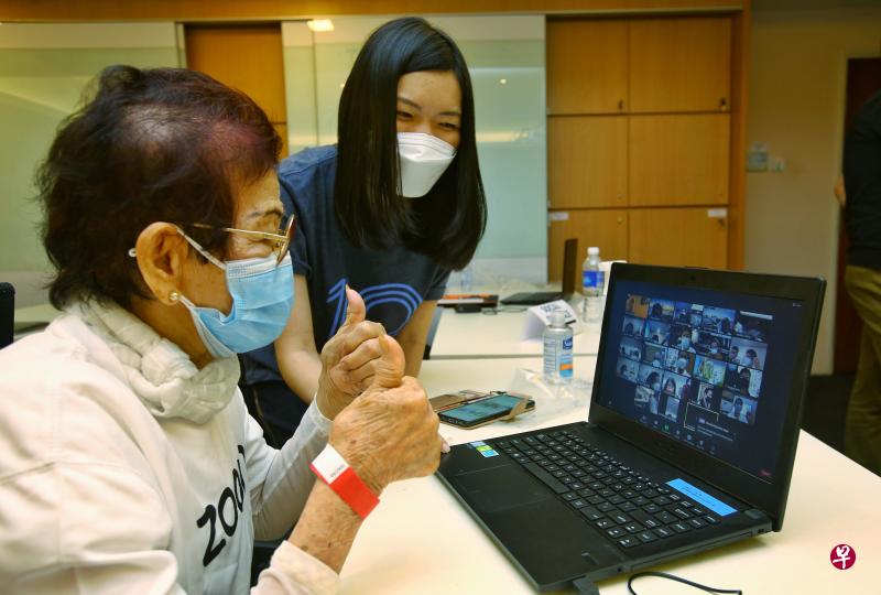Zoom的员工叶慧俐（右）当义工，在工作坊教导81岁的蔡萍海如何使用Zoom进行视频通话。（陈福洲摄）