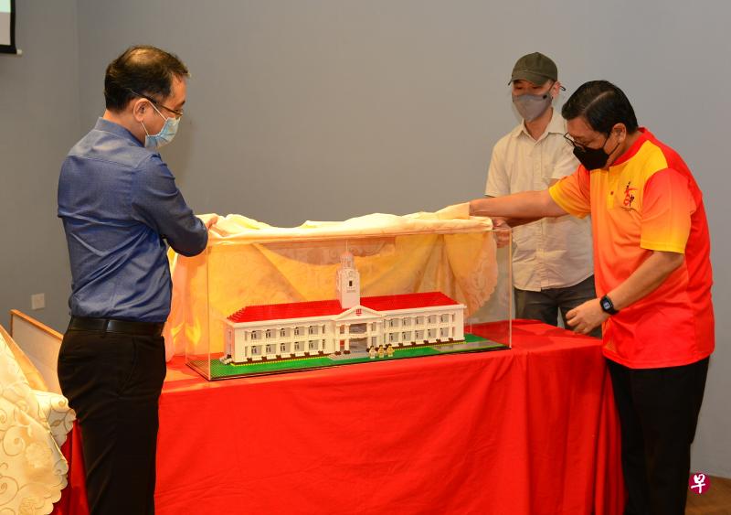 华中校友会会长黄龙金（右起）、“乐高钟楼”创作者邝家乐与华中校长彭俊豪为模型揭幕。（华中校友会提供）