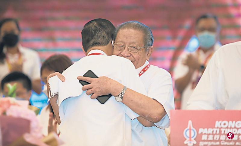 民行党元老林吉祥（右）昨天在民行党全国大会宣布引退后，他的儿子、原任秘书长林冠英（背对镜头者）随即上前拥抱父亲。不过，林吉祥过后仍出人意料地获受委党务资政。（星洲日报）