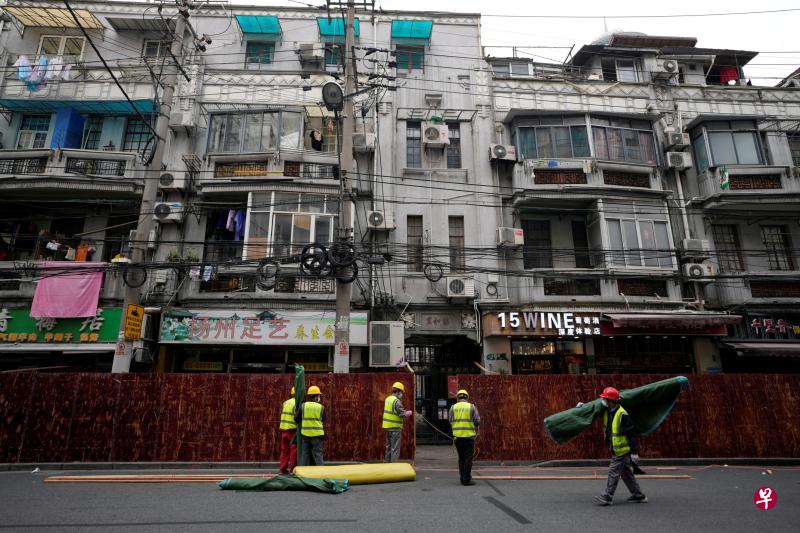 上海浦西地区今天凌晨起实施封控，建筑工人昨天在居民区外搭建隔离屏障。（路透社）