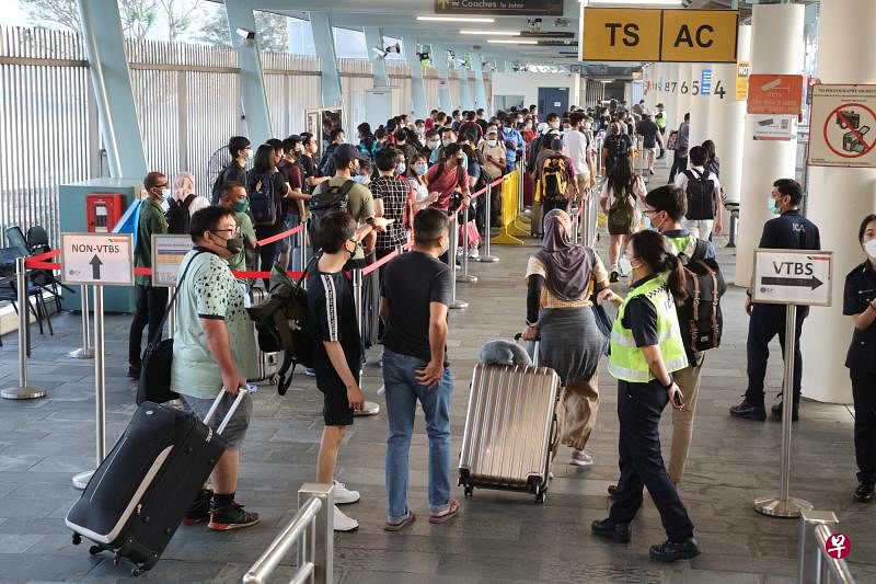 进出新马的旅客昨天起可乘搭汉达英达公司提供的短程巴士服务，往返新山关卡综合大厦和兀兰关卡。一些行装轻便的旅客因排队等巴士的人龙而却步，索性徒步越堤。（唐家鸿摄）