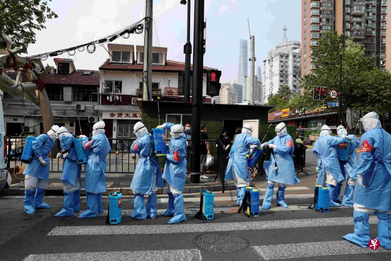 昨天一队身穿全套防护衣的工人，准备在上海黄浦区一个居民楼进行消毒杀菌。（路透社）