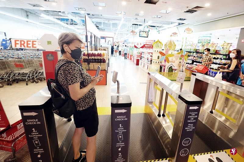 公众进入大多数场所不再需要使用合力追踪应用或便携器登记。裕廊坊内的超市昨天还未将SafeEntry自动闸门和感应器拆除，有公众不清楚这项措施已解除，在进入超市前仍拿起手机试图登记。（蔡家增摄）