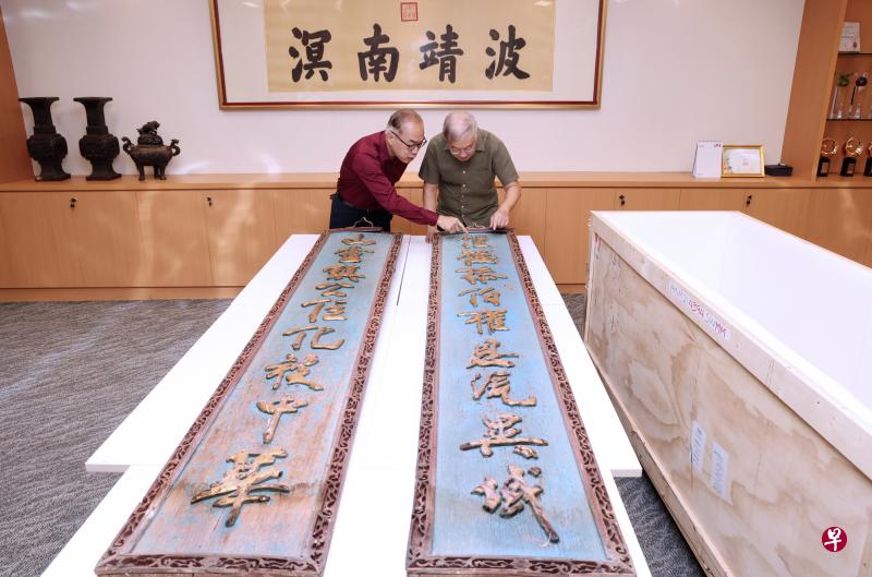福建会馆将一副属于我国华人古庙恒山亭的楹联从美国运回新加坡。福建会馆名誉理事杜南发（右）和文化组副主任许振义博士（左）上周三在会馆会议室见证这件文物运抵，两人过后仔细查看文物。（梁麒麟摄）