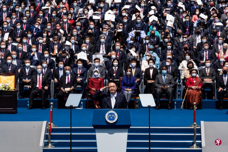 韩国总统尹锡悦昨天在首尔国会议事堂前的国会广场宣誓就职时，向出席观礼者敬礼。出席仪式的各国政要与贵宾，包括我国总统哈莉玛和夫婿莫罕默德（前排左三与二）、中国国家副主席王岐山（前排左一），以及去年底获特赦出狱的韩国前总统朴槿惠（前排右三）。（彭博社）