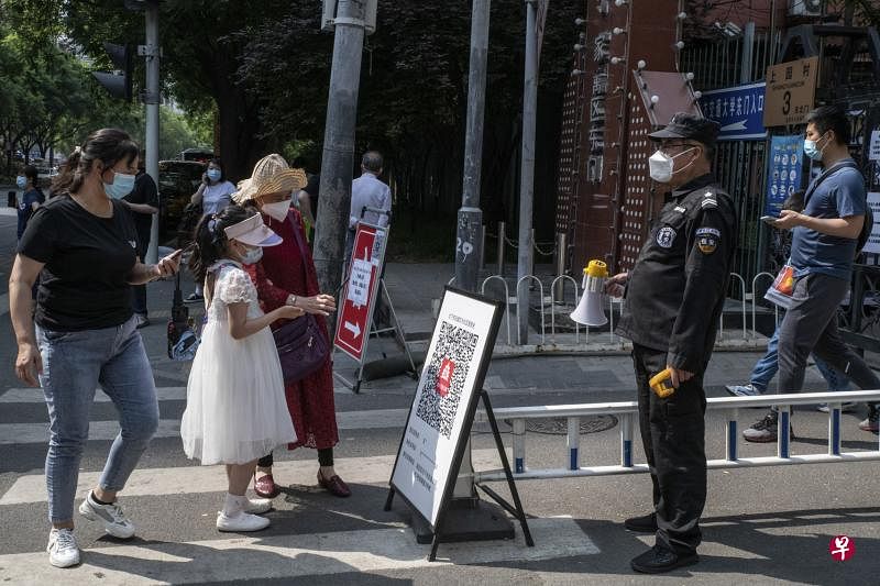 北京市为了强化对小区、村封闭式管理，在提级管控重点区域严格要求做到查验健康码及24小时内核酸检测阴性证明。图为居民昨天在北京一处小区入口处，用手机扫描健康二维码。（彭博社）