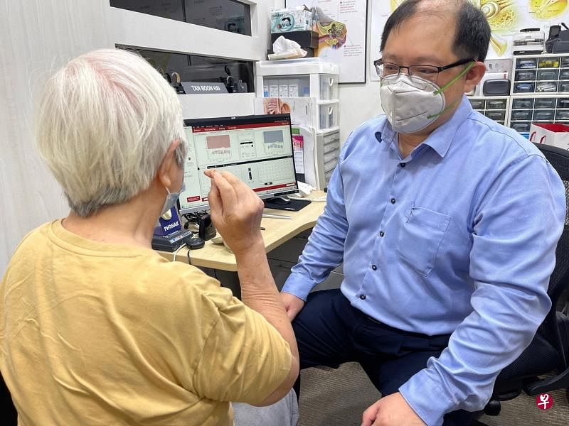陈文海（右）给胡女士测试最新蓝牙助听器。