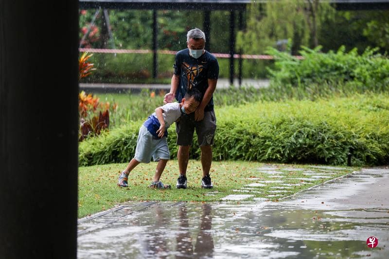 大雨中，父子戏耍玩闹的片刻，连雨滴都蹦跳得格外欢腾。（白艳琳摄）