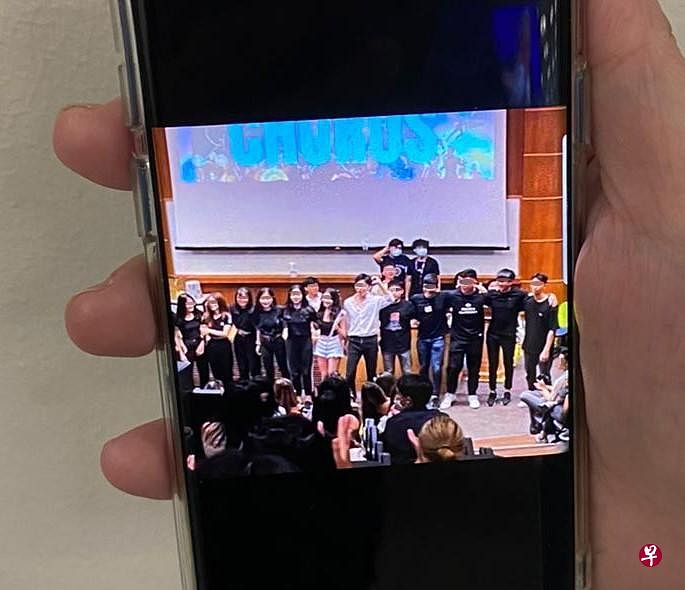女生出示新生们在室内聚在一起进行表演时的情况，一些台上台下的人没戴好口罩。（受访者提供）