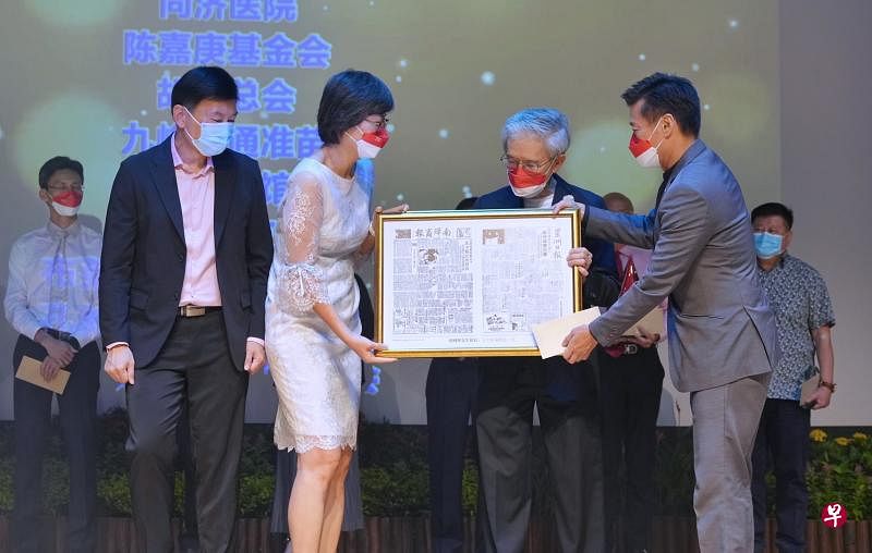 新报业媒体华文媒体集团社长李慧玲（左二）和《联合早报》总编辑吴新迪（右一）在捐款仪式上赠送印有《南洋商报》和《星洲日报》封面的纪念品给胡财辉（右二），报章出版日是胡财辉出生的那一天。捐款仪式由晚会主宾交通部兼财政部高级政务部长徐芳达（左一）见证。（谢智扬摄）