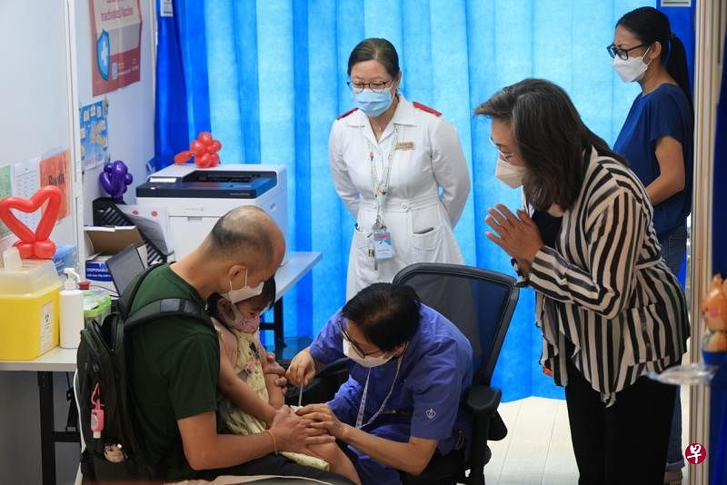 香港特区政府​公务员事务局局长杨何蓓茵（右），8月15日上午在香港儿童医院儿童社区疫苗接种中心陪小朋友打针。（香港中通社）