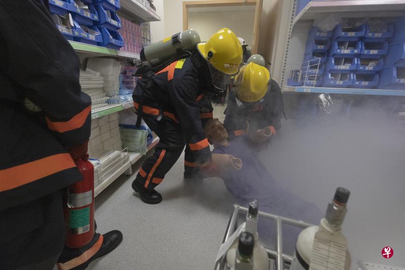 邱德拔医院的紧急应变小组赶到火场后，查看火势并解救困在储藏室的伤者。（陈来福摄）