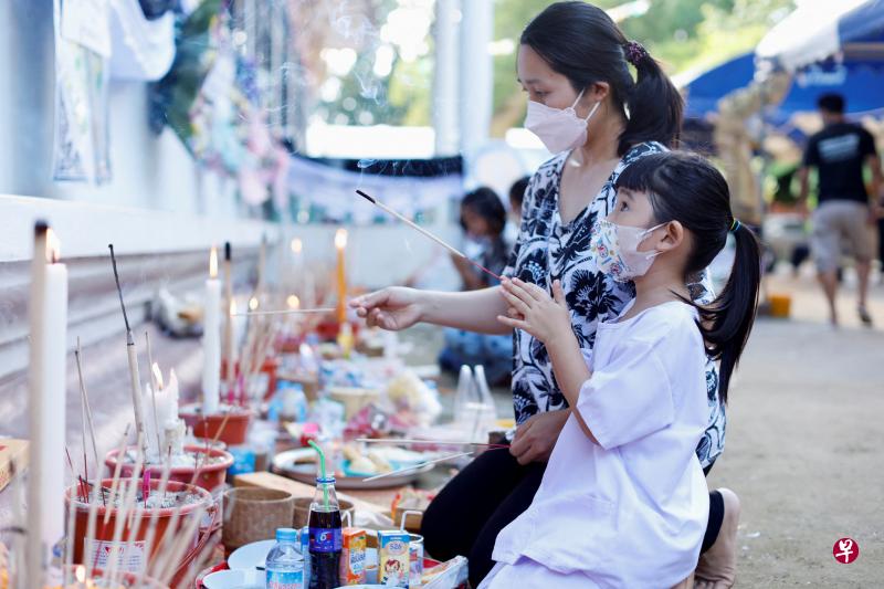 泰国民众星期六来到乌泰沙旺镇的一所寺庙，向停柩在寺庙的托儿所凶杀案受害者上香哀悼。（路透社）