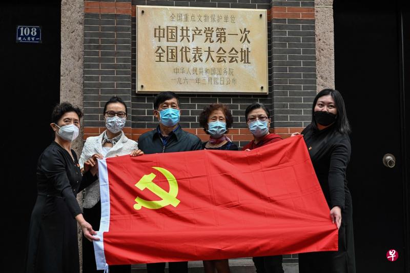 10月16日几名戴着防护口罩的游客手持一面中国共产党党旗，在上海市黄埔区兴业路的中共第一次全国代表大会会址前合照。（法新社）