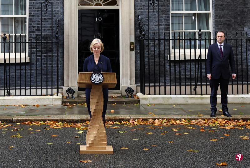 在落叶遍地的唐宁街10号门外，英国首相特拉斯宣布辞职，担任首相仅仅半个秋天。她的丈夫奥利瑞陪伴在后。（路透社）