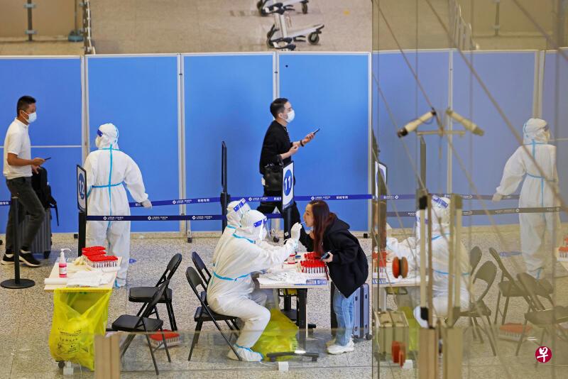 中国官方据传正探讨进一步缩短入境旅客的集中隔离天数，从原来的七天大降至两天。图为上海虹桥国际机场工作人员正在为旅客做核酸检测。（路透社）