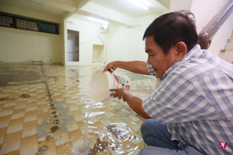  苏先生用水桶和海绵处理积水，称他一个人要花6个小时才能完成清理工作。  （潘丰源 摄影）